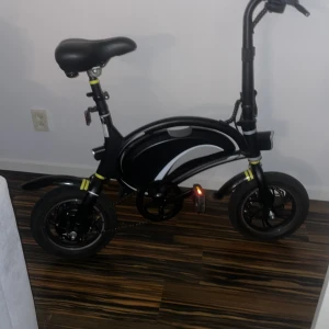 FREEV Elcykel - Kompakt elcykel från FREEV i svart med LED-display och justerbar sadel. Cykeln är i gott skick med minimalt slitage, perfekt för stadspendling. Utrustad med bak- och framljus samt reflexer för ökad säkerhet. Laddningsport och batteri integrerat i ramen.