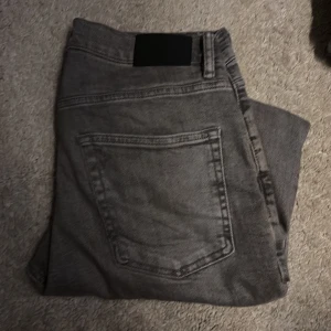 Grå jeans från Zara, storlek 40 - Säljer ett par grå jeans från Zara i storlek 40. De har klassisk femficksdesign, raka ben och normal passform. Jeansen är tillverkade i bomull och har en snygg, lite tvättad look. Perfekta för dig som gillar stilrena och enkla jeans.
