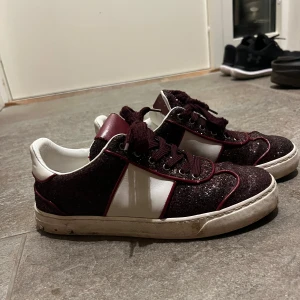 !INTRESSELOLL!  Valentino Fly Crew glitter - Snygga Valentino Fly Crew skor i vinrött glitter med vita skinnpaneler och mörkröda detaljer. Skorna har snörning, rund tå och coola nitar på hälen. Yttersulan har ett unikt camouflagemönster. Perfekta för dig som vill sticka ut med stil. Några nitar har lossnat men man kan köpa nya och sätta fast. (Tvättas och rengörs innan köp)