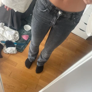 Grå bootcut jeans med normal passform - Säljer ett par grå jeans med bootcut-snitt och normal passform. Jeansen har klassisk femficksdesign, knapp och dragkedja framtill samt bälteshällor. Materialet är jeans och färgen är en snygg tvättad grå nyans. Perfekta för dig som gillar en stilren look.