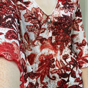 Blommig orange och vit blus med v-ringning - Säljer en blus med orange blommig print med vit bakgrundsfärg . Blusen har v-ringning med en liten spetskant och ett dekorativt hänge framtill. Ärmarna är trekvarts och har volangkant. Materialet är tunt och lätt, perfekt för vår och sommar. Storleken är large men passar lite lösare också snyggt på mig som är storlek small. I väldigt bra skick förutom ett litet hål i armhålan som lätt kan sys ihop med ett par stygn.