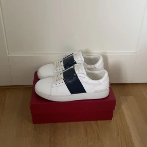 Valentino Garavani Open sneakers vit/blå - Säljer ett par snygga Valentino Garavani Open.  kommer med originalkartong som har en defekt (bild), dustbag och påse. Inte äkta men kan gå med på ett bra pris 