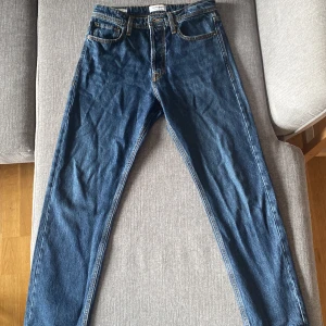Mörkblå jeans från Jack & Jones - Säljer ett par klassiska mörkblå jeans från Jack & Jones (Jeans Intelligence) med raka ben och relaxed passform i storlek W29 L30. Jeansen har snygga kontrastsömmar, läderpatch bak i midjan och är i relativt nyskick då byxorna knappt är använda. Perfekta för dig som gillar enkel och tidlös stil. Jag som bär byxorna på bilden är 170cm lång.