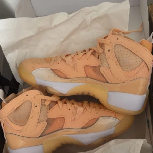 Peachfärgade sneakers med mesh och skinn - Säljer ett par riktigt snygga sneakers i peach och beige toner. Skorna har en cool mix av mesh och skinnpaneler, samt en chunky sula i gummi. De har snörning och en sportig vibe som sticker ut. Perfekta för dig som vill ha något unikt på fötterna.