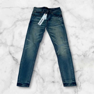 Blå jeans från Purple Brand, stl 32 - Snygga blå jeans från Purple Brand i klassisk femficksmodell. Jeansen har en tvättad look med slitningar och raka ben. Tillverkade i jeansmaterial med detaljer som kopparfärgade nitar och patch bak i midjan. Perfekta för dig som gillar streetwear och stilren denim.
