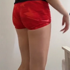 Nike Pro röda träningsshorts - Nike Pro shorts i rött med grafiskt mönster och bred resår med logga. De är tighta och sitter högt i midjan, perfekta för gymmet eller sport. Materialet är stretchigt polyester som andas och ger bra rörelsefrihet. Snyggt och sportigt vibe!