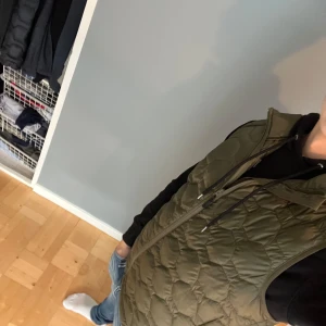 Olivgrön quiltad dunväst från Björn Borg - Säljer en olivgrön quiltad dunväst från Björn Borg med dragkedja framtill och hög krage. Västen har ett snyggt hexagonmönster och är tillverkad i polyester. Perfekt att slänga över en hoodie för en chill look.