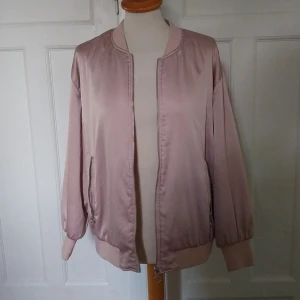 Ljusrosa bomberjacka från Zara Basic - Säljer en ljusrosa bomberjacka från Zara Basic. Jackan har klassisk bombermodell med ribbade muddar, dragkedja framtill och två fickor med dragkedja. Materialet är glansigt och känns mjukt mot huden. Perfekt för dig som vill ha en stilren och trendig jacka.