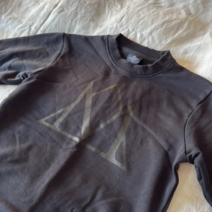 Svart sweatshirt från Mountain Horse XS - Svart sweatshirt från Mountain Horse i storlek XS. Tröjan har ett stort tryckt logomärke framtill och texten 'Mountain Horse' på ryggen. Klassisk rund halsringning och ribbade muddar vid ärmslut och nederkant. Perfekt för dig som gillar stilren och sportig look.