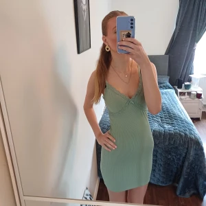 Grön ribbad klänning från H&M Divided - Supersöt ljusgrön ribbad klänning från H&M Divided i storlek XS även om man har storlek S så passar den super.Klänningen har spetsdetaljer vid urringningen, smala axelband och en liter roset dör fram och  tajt passform. Perfekt för varma sommardag. Materialet är mjukt och stretchigt för skön komfort. Kort klänning. Skriv om ni har några fråger 