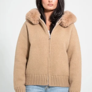 Beige stickad jacka med pälsluva - Snygg beige stickad jacka med fluffig päls runt luvan. Jackan har dragkedja framtill, ribbade muddar och en loose passform. Perfekt för dig som vill ha en mysig och trendig look under höst och vinter💕användt 2 gånger då det inte riktigt är min stil. Pris kan diskuteras!