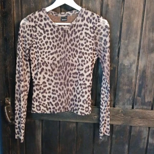 Leopardmönstrad mesh topp Gina Tricot - Säljer en långärmad mesh topp från Gina Tricot i storlek S. Toppen har ett snyggt leopardmönster i beige och bruna toner, är figurnära och har rund halsringning. Perfekt för dig som vill sticka ut med ett djurmönstrat plagg. Be om bilder på om ni vill se hur den sitter! Köptes för 300 säljs för 150
