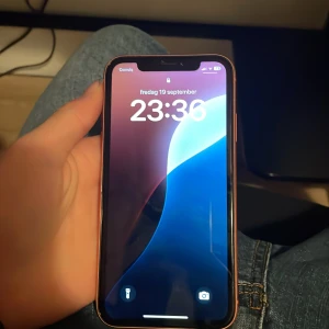 iPhone XR - Snygg iPhone XR i orange färg, med 6,1-tums skärm och Face ID. Mobilen ser ut att vara i gott skick utan synliga repor eller skador på skärm eller baksida. Kameran och knappar är intakta. Perfekt för dig som vill ha en pålitlig och stilren iPhone till ett bra pris. Pris kan också diskuteras 