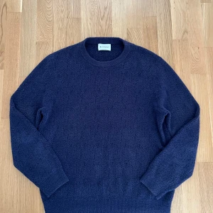 Mörkblå stickad tröja från Dondup - Mysig mörkblå stickad tröja från Dondup med rund halsringning. Tröjan har en enkel och stilren design med ribbade muddar vid ärmslut och nederkant. Perfekt för dig som gillar klassiska och bekväma plagg med italiensk känsla.