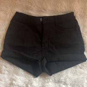 Svarta jeansshorts från Lindex - Svarta jeansshorts från Lindex med klassisk femficksdesign, uppvikta benslut och dragkedja med knapp framtill. Snygg och enkel modell som är lätt att matcha med allt. Perfekt för dig som gillar stilrena och bekväma shorts.