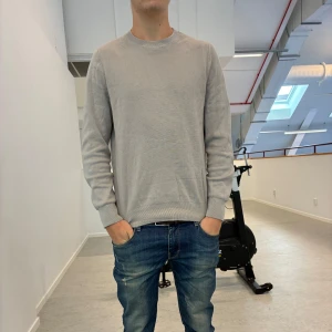 Ljusgrå stickad tröja - En stilren ljusgrå stickad tröja med rund halsringning och ribbade muddar. Tröjan har en klassisk passform och är perfekt för lager-på-lager. Enkel design utan mönster eller logga, passar till allt och är superenkel att matcha. Modellen är 182 och väger 70 kg och bär storlek M!🫠