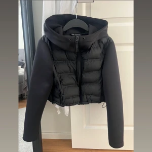 Zara jacka - Säljer en svart croppad pufferjacka från Zara med huva och dragkedja framtill. snörena är inte kvar på luvan. Funkar bra på S men denna jackan är L pågrund av att jag ville ha mer oversize💕