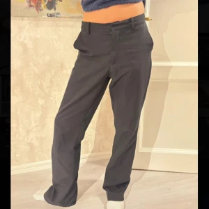 Svarta kostymbyxor från BikBok - Klassiska svarta kostymbyxor från BikBok i rak modell med medelhög midja. Byxorna har hällor för bälte, diskreta fickor bak och stängs med dragkedja och knapp framtill. Perfekta för en clean och stilren look.