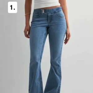 Blå bootcut jeans med dubbla knappar - Snygga ljusblå jeans med bootcut-modell och dubbla knappar i midjan. Jeansen har klassiska fickor fram och bak, samt markerade sömmar för en trendig look. Perfekta för dig som gillar en avslappnad men ändå stilren stil.