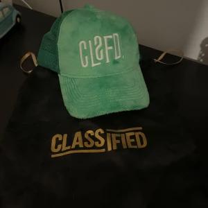 Grön keps från Classified med mesh - Exklusiv Snygg grön keps från Classified som inte säljs längre! med CLSFD-brodyr framtill. Framsidan är i mjuk plysch och baksidan har meshpaneler för extra ventilation. Kepsen har böjd skärm och justerbar passform. Perfekt accessoar för en cool streetstyle. Du får även med dustbagen till kepsen! Använd ca 1-3 gånger🙌🤩