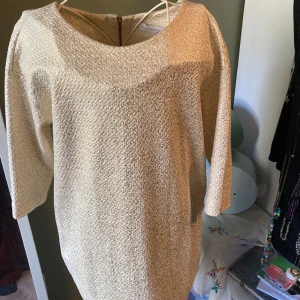 Tunika/klänning  - Vitguldig klänning/tunika som passar fint på vårkanten till jeans eller tights. Trekvartsärm, dragkedja baktill med liten hasp.