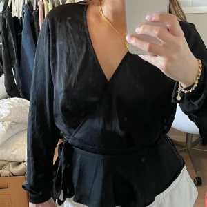 Satin topp - Långärmad omlott-topp. Glansigt tunt material. Från Nelly. Peplum-topp  Jättefint skick!