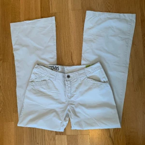 Lågmidjade byxor  - Beigea/vita lågmidjade tygbyxor i 100% bomull.  Innerbenslängd: 78cm Midjemått rakt över: 40cm