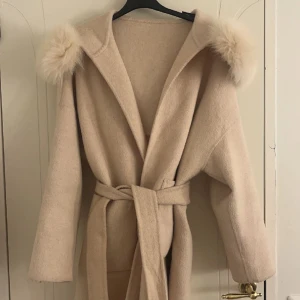Beige kappa med päls  - Detta är en beige kappa med äkta päls i storleken xs men den är ganska stor i storleken så funkar för S oxå. Den är i nyskick då jag bara har använt den 2 gånger. Köptes för 6000 men säljer nu för 1400. Finns i Göteborg!