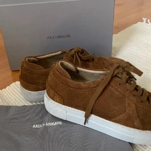 Axel arigato skor - Säljer mina bruna skor från Axel Arigato i väldigt fint skick. Storlek 39. Unik färg som är svårare att få tag på.