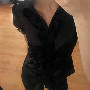 Skjort blus - En svart blus med knappar och puffärmar, aldrig använd.  Fint skick 