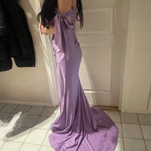 Lila mermaid klänning - En lila klänning i en mermaid cut, rosett band på armarna och slits vid benen. Använt en gång. Funkar för 36-38/s-m   Originalpris på 3500:-