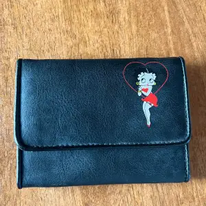 Super fin Betty Boop plånbok. Ny skick. Helt oanvänd. 5 kortfack och ett stort fack för exempelvis sedlar. Knapp stängning. Finns även ett dragkedje stängbart fack💗