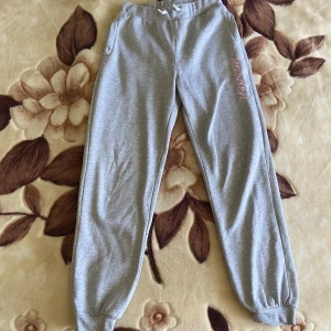 Grå mjukisbyxor från On The Peak - Grå mjukisbyxor med rosa brodyr ”Sweden” på vänster ben från On The Peak. I mycket fint skick. Storlek 170 men passar XS-S. Stretchiga, sköna och varma med normal waist. 