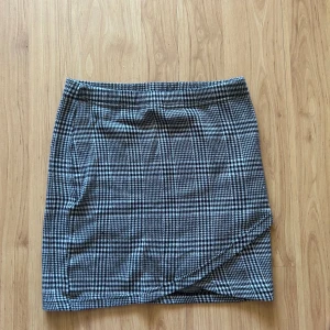 Rutig kort kjol - Kort kjol med en skurning framtill. Materialet är stretchigt och lite tjockare. Bra skick, använd ett fåtal gånger bara!