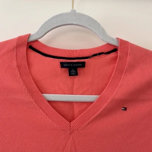 Tommy Hilfiger tunn v-tröja - Tommy Hilfiger tröja i pastellrosa färg. Något skrynklig på bilden men är bara för den legat i min garderob och inte använts på länge. En tvätt och upphängning senare är den på topp igen. I storlek XS men passar nog också S