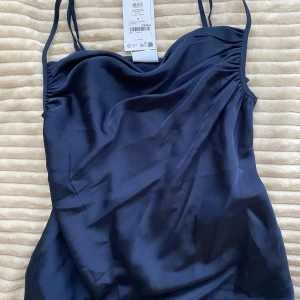 Topp med rynk  - Marinblått linne med rynk vid axelbandet . Aldrig använd med prislapp kvar . 