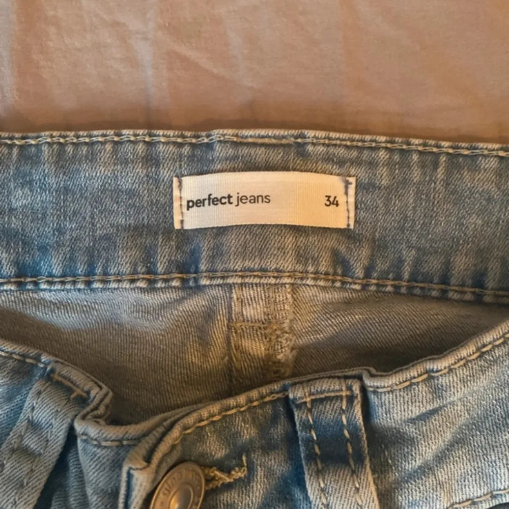 Ett par ljusblå jeansbyxor från Perfect Jeans / gina i storlek 34. Byxorna har en klassisk femficksdesign och är tillverkade i denim. De har en bootcut-stil och är lågmidjade.. Jeans & Byxor.