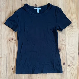 Svart t-shirt från H&M - En enkel och stilren svart t-shirt från H&M i storlek XS. T-shirten har korta ärmar och en rund halsringning. Den är oanvänd men utan prislapp! Hör gärna av dig vid frågor💞