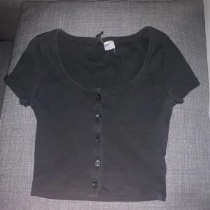 Svart basic T-shirt med svarta knappar på - En svart jätte snygg basic T-shirt med svarta knappar på. Skön och jätte söt t-shirt.