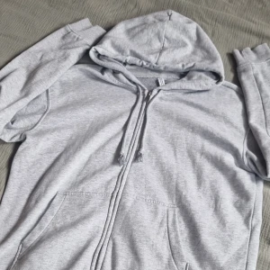 Grå kofta  - Grå kofta med dragkedja. Strl. S från HM basic. Luva och snören. 