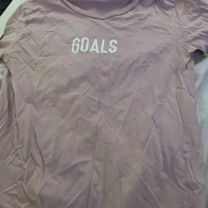 Ljus rosa t-shirt med text - Ljus rosa t-shirt med en text vid bröstet ( goals) ( köparen står för frakt)