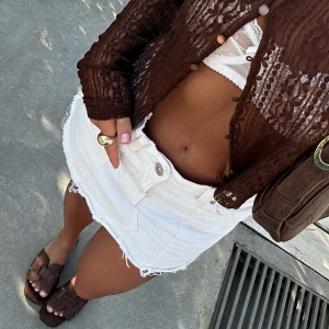 Vit jeanskjol - Säljer en snygg vit jeanskjol som är perfekt för sommaren! Kjolen är kort och har en rå kant nertill som ger en cool och avslappnad look. Den har också stora fickor fram och en knapp- och dragkedjestängning. Passar perfekt till en dag på stan eller en sommarfest! 💛