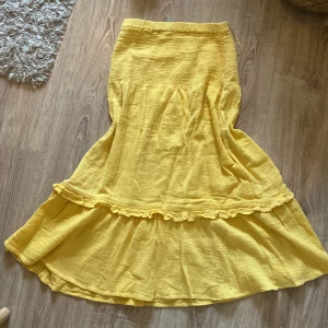 Gul långkjol från Amelie & Me - Säljer en superfin gul långkjol från Amelie & Me i storlek XS. Kjolen har en härlig volangdetalj och är perfekt för sommaren. Den är gjord av ett lätt och luftigt material som känns skönt mot huden. Passar perfekt till både vardag och fest!💕