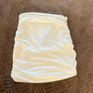 Vit satin kjol - Säljer en superfin vit kjol. Den är kort och har en tight passform med snygga rynkdetaljer på baksidan. Perfekt för fest eller en utekväll! 🥳 köptes för 129kr och säljs för 15kr. 