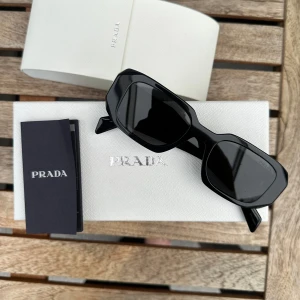 Prada solglasögon  - Superfina solglasögon från Prada i bra skick. Svarta. Självklart äkta. Allt är orginal såsom kartong, fodral och dukar. Finns några (supersmå) prickar på ena glaset, syns mycket lite och märks inte av. Såg detta vid tvätt.   Nypris 3500kr