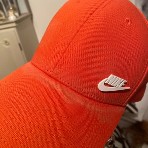 Nike keps - Nike keps  Fått lite färgfällning vid söm framtill se bild. Orange. Onesize.  