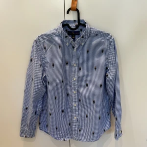 Ralp Lauren skjorta 14-16 år - Ralph Lauren skjorta med RL nallebjörnen. Blå och vit. Knappt använd, nyskick. 14-16 år. 