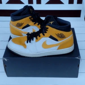 Air Jordan 1 Mid White/University Size 11 Gold-Black 554724-170 - Säljer ett par Air Jordan 1 Mid i färgerna gul, svart och vit. Skorna är i gott skick och kommer med originalboxen.   Strl: EUR 45  Skriv gärna vid frågor :)