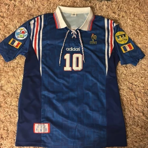 Frankrike VM 1996-1997 hemmaställ (ZIDANE) fotbollströja - En helt oanvänd zidane tröja från 1996-1997 VM. Nästan omöjlig att få tag i. Nypris ca 2600. Väldigt ovanliga tryck och detaljer. Vid fler frågor är det bara att skriva. 