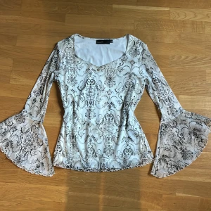 Långärmad - Långärmad tröja med mönster och en fin berlock vid halsringniningen. Storlek 36/38, S-M. Fint skick. Tunnare lite genomskinligt material vid armarna💗